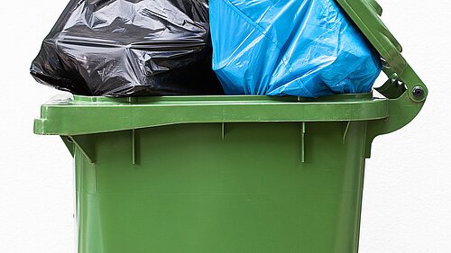 A wheelie bin overflowing with rubbish.